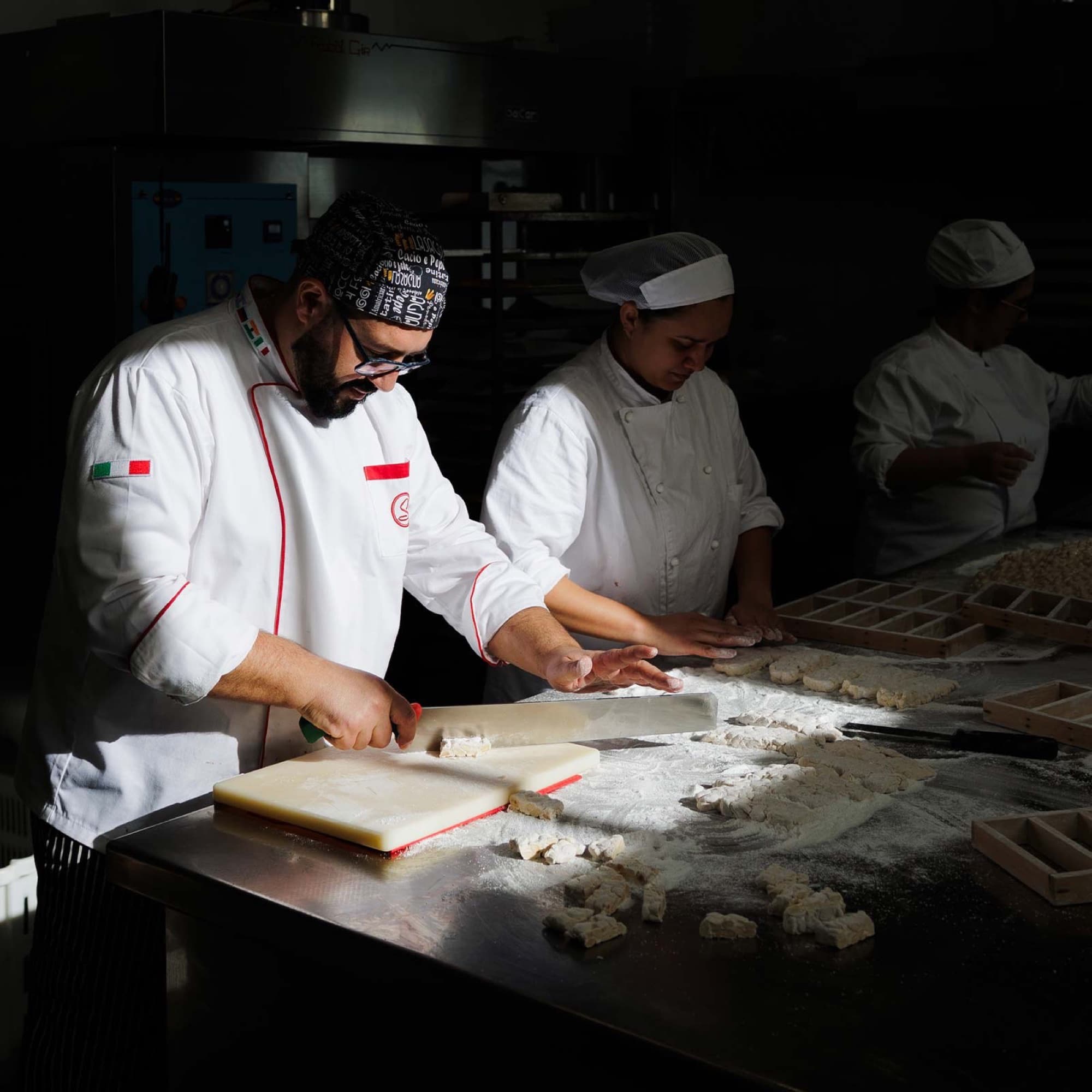 Pasticceri al lavoro sul banco del laboratorio