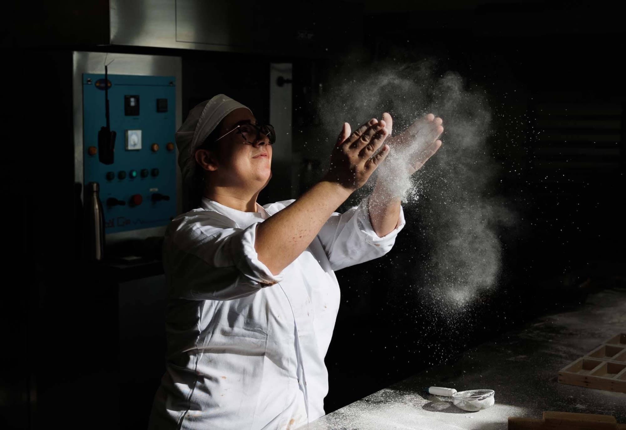 Una pasticcera spolvera la farina nel laboratorio